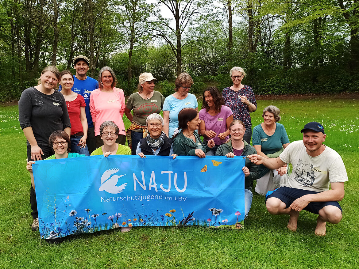 Um ein hellblaues NAJU-Banner versammeln sich die Teilnehmenden der Wilden Spiele in Mammendorf
