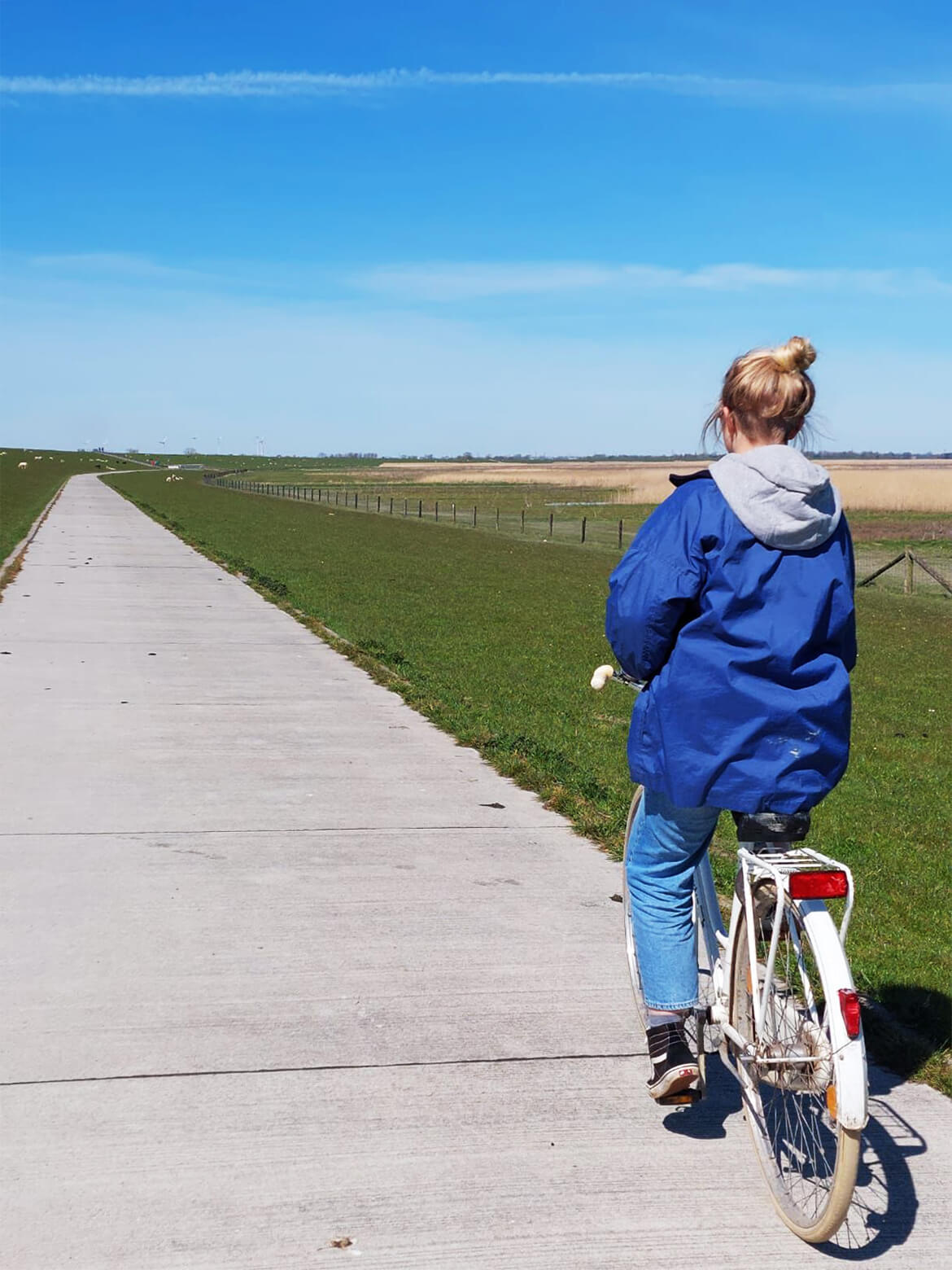 Lily fährt auf ihrem weißen Fahrrad einen geradlinigen Radweg entlang