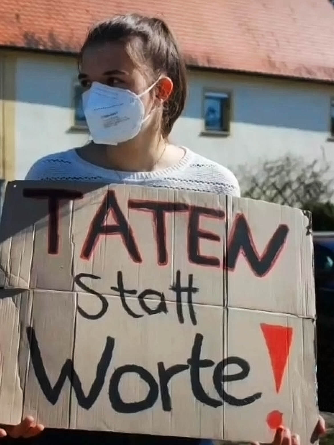 Johanna Fuchs mit FFP2-Maske hält ein Schild mit Aufschrift Taten statt Worte