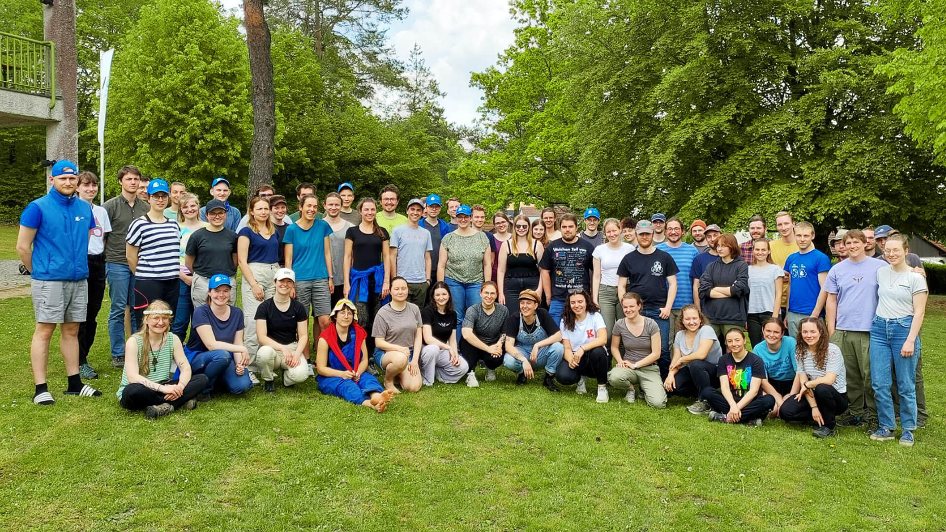 Eine sehr große Gruppe an Teilnehmer:innen des Artenkenntnis-Wochenendes stehen zusammen auf einer grünen Wiese