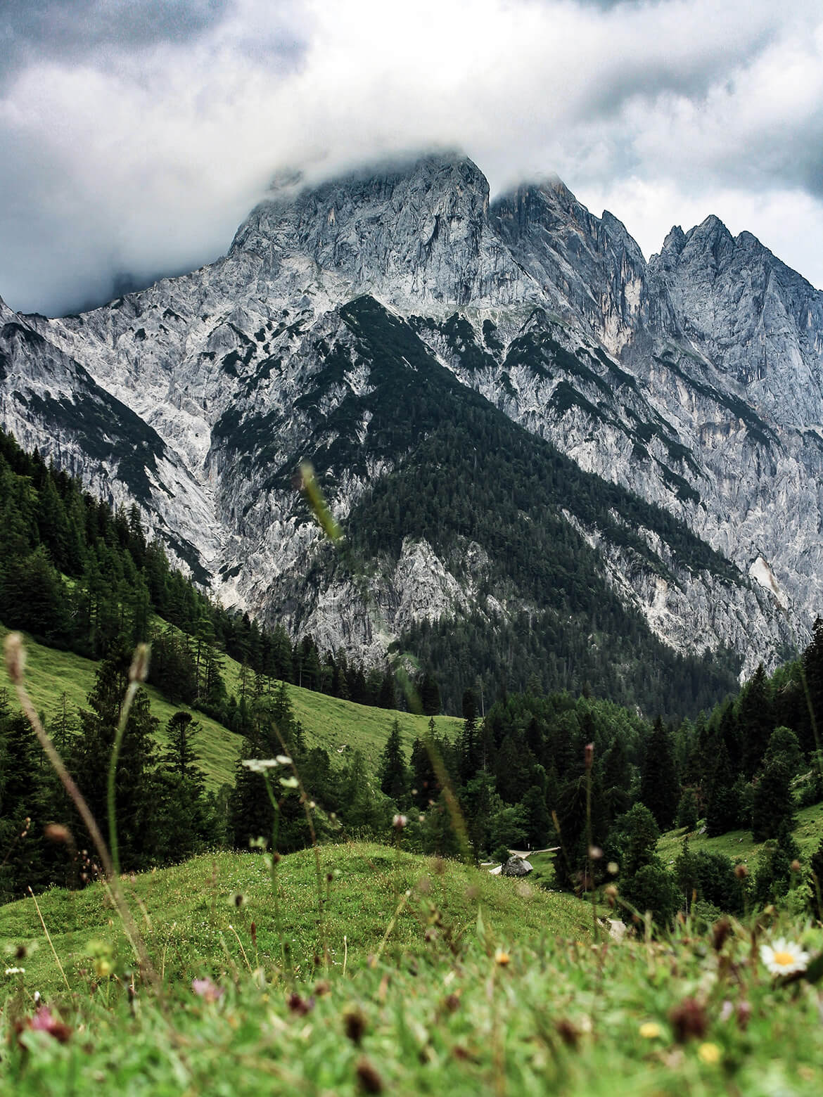 Blick von oben herab ins Klausbachtal, in Hintergrund verschwindet die Spitze eines beeinduckenden Berges in den Wolken